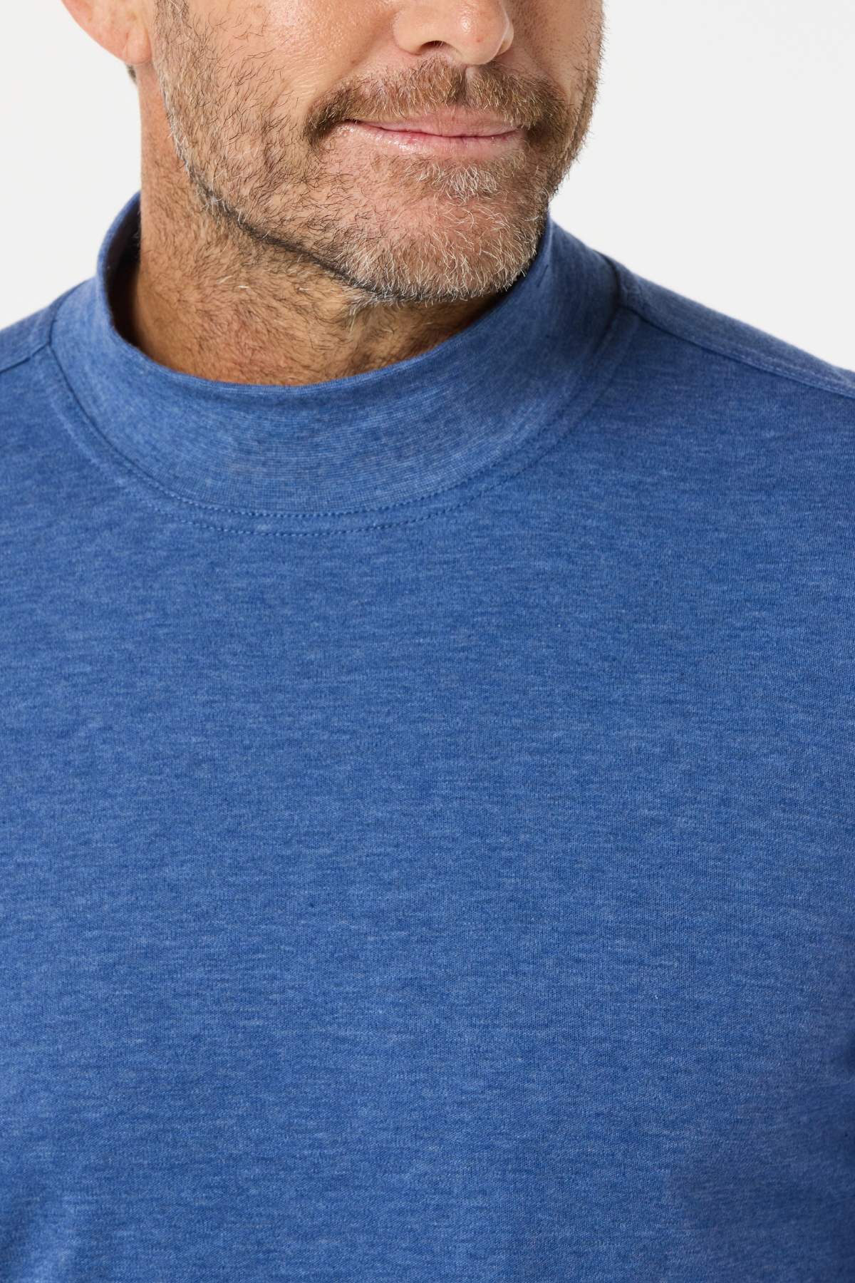 A close-up of a man wearing the Breakaway Skivvy in blue, featuring a classic mock neck style in a polyester-cotton blend, with his lower face, neck, and chest visible against a plain white background.