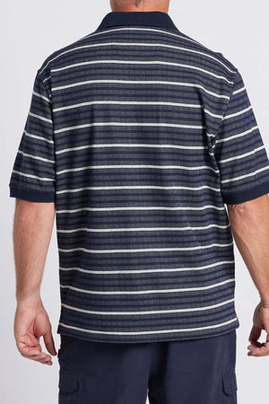 A man is shown from the back wearing a Breakaway Turner Micro Prima Polo, featuring a navy collar with horizontal stripes in various shades of blue, gray, and white. He has light skin and short hair, and he is also wearing dark pants.