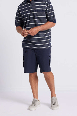 A person wearing a Breakaway Turner Micro Prima Polo in navy blue and white stripes, paired with navy blue cargo shorts and gray sneakers, stands against a plain white background.