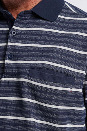 Close-up of a person wearing the Breakaway Turner Micro Prima Polo, showcasing its distinctive navy collar and white horizontal stripes. The shirt features a buttoned placket with three buttons and includes a small chest pocket. A portion of the person's neck and shoulder is visible.