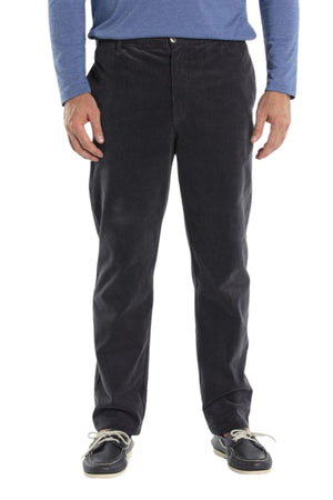 A person stands against a white background wearing a blue long-sleeve shirt, Breakaway Woodbury Pull On Pant in black with an elastic waist, and black boat shoes with white laces.