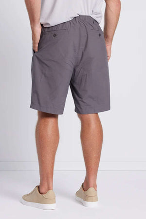 Back view of a person wearing the Breakaway Woodbury Short with an adjustable waist, a gray T-shirt, and beige sneakers. The shorts feature buttons on the back pockets, and the person is standing against a plain, light-colored background.