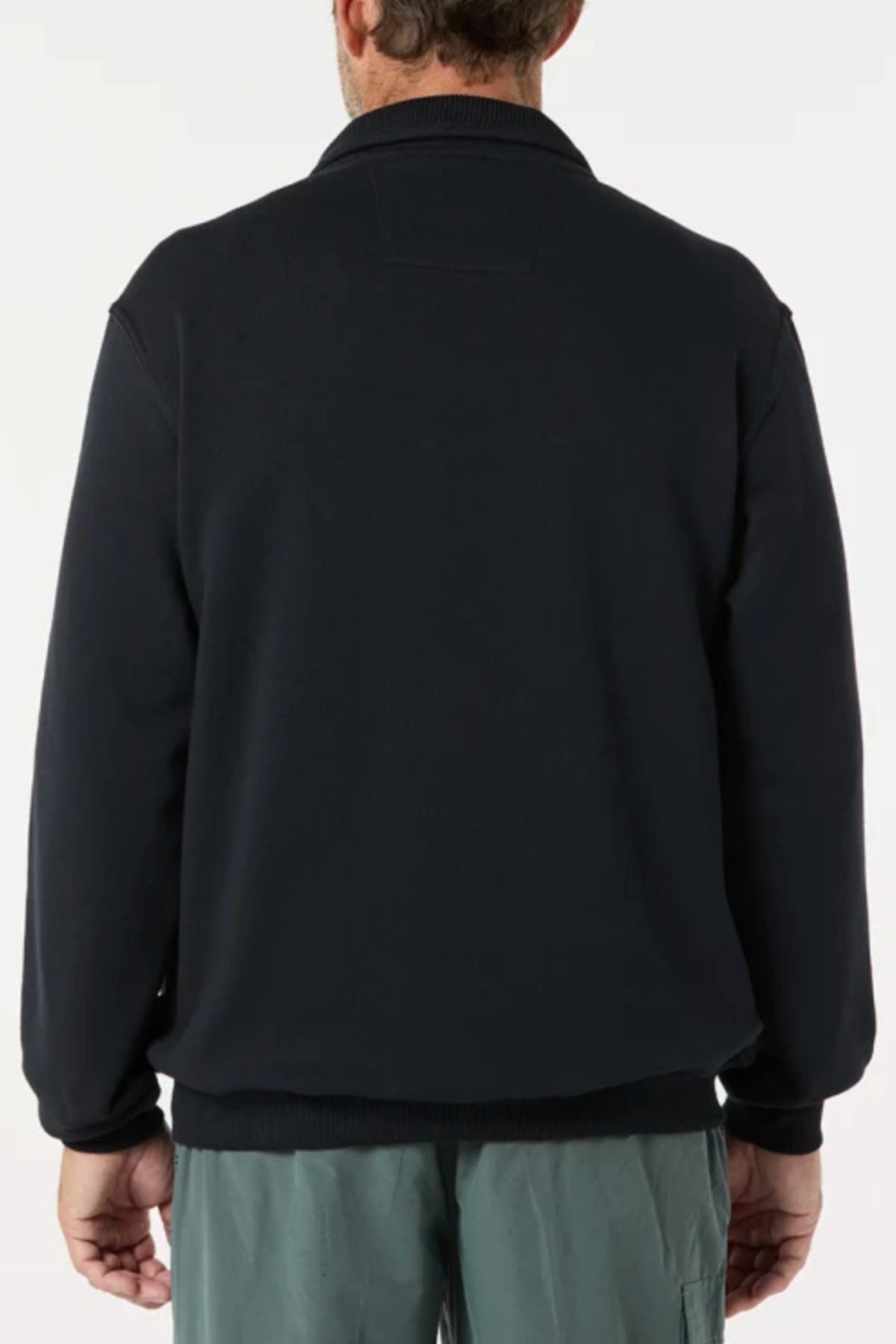 A person is shown from the back wearing the black Breakaway Zed Snowy Mt Fleece Jacket with green pants. The background is plain and light-colored, and their hands are relaxed at their sides.