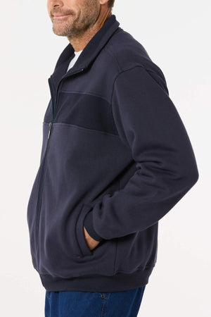 A man models the Breakaway Zed Snowy Mt Fleece Jacket in navy blue, hands in pockets, standing against a white background and smiling—ideal for winter layering.
