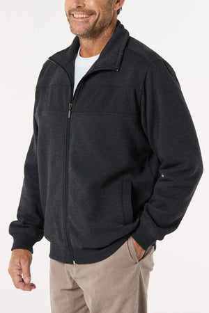 A smiling man wears the Breakaway Zed Snowy Mt Fleece Jacket over a white shirt and tan pants, standing with one hand in his pocket against a plain light background.