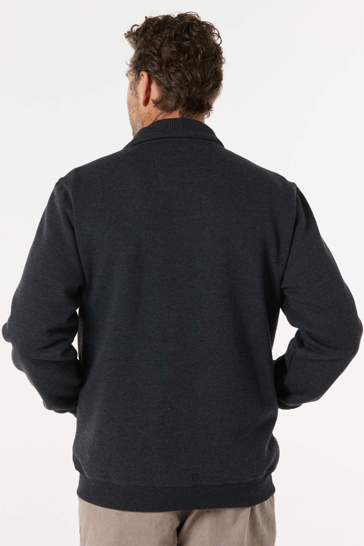 A man with curly brown hair, seen from behind, wears the Breakaway Zed Snowy Mt Fleece Jacket and light pants against a plain light background—an ideal winter look.