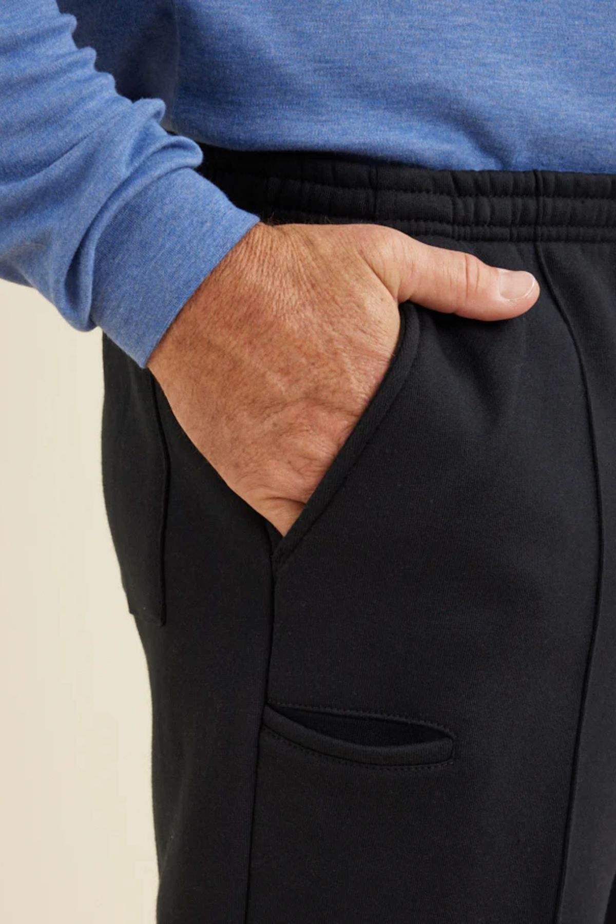 A person is wearing Breakaway Pocket Snowy Mt Fleece Pant with an elasticated waist and has their right hand in the pocket.