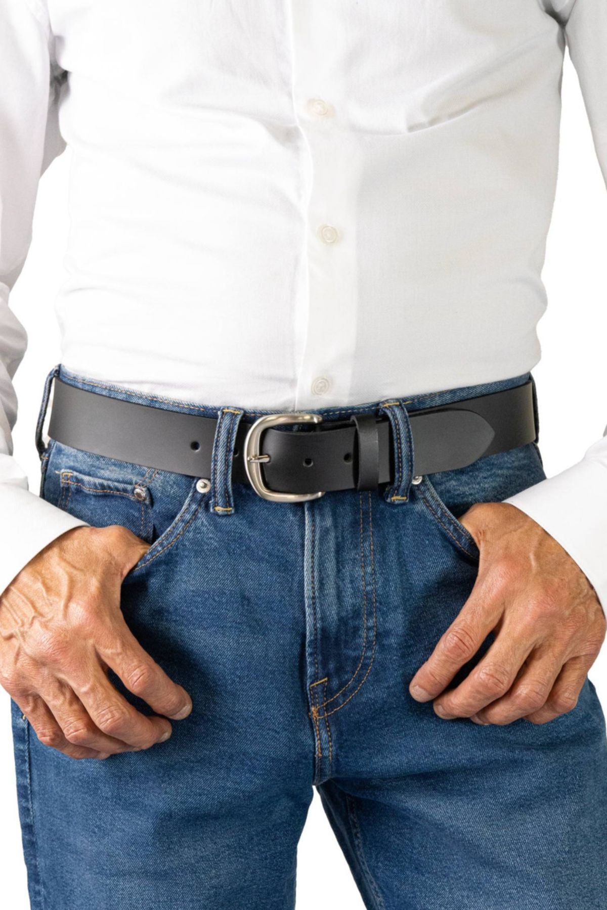 A person stands with hands on hips, wearing a white button-down shirt tucked into blue jeans, accessorized with the Buckle 5092 Buffalo Top Grain Belt.