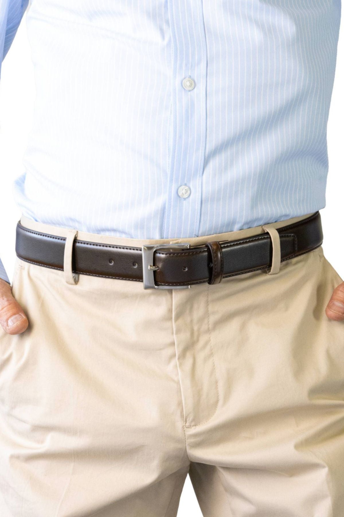 A person wearing a light blue striped dress shirt tucked into beige pants with the Buckle 5115 Rogue Deluxe Leather Belt, hands resting in pockets.