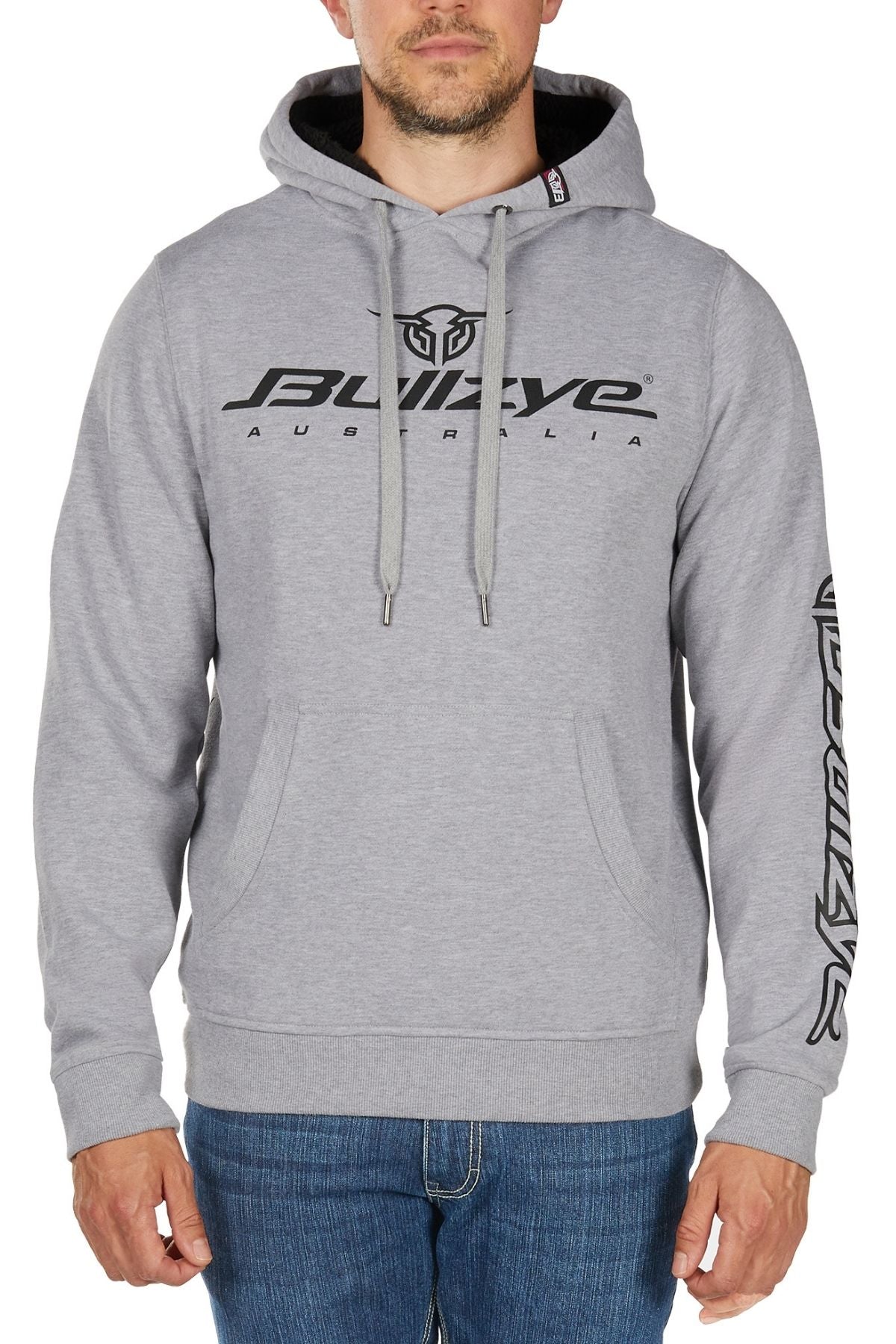 A man wearing the Bullzye Determination Hoodie—a light gray premium hoodie with bold "BULLZYE AUSTRALIA" graphics on the chest and sleeve logo—paired with blue jeans.