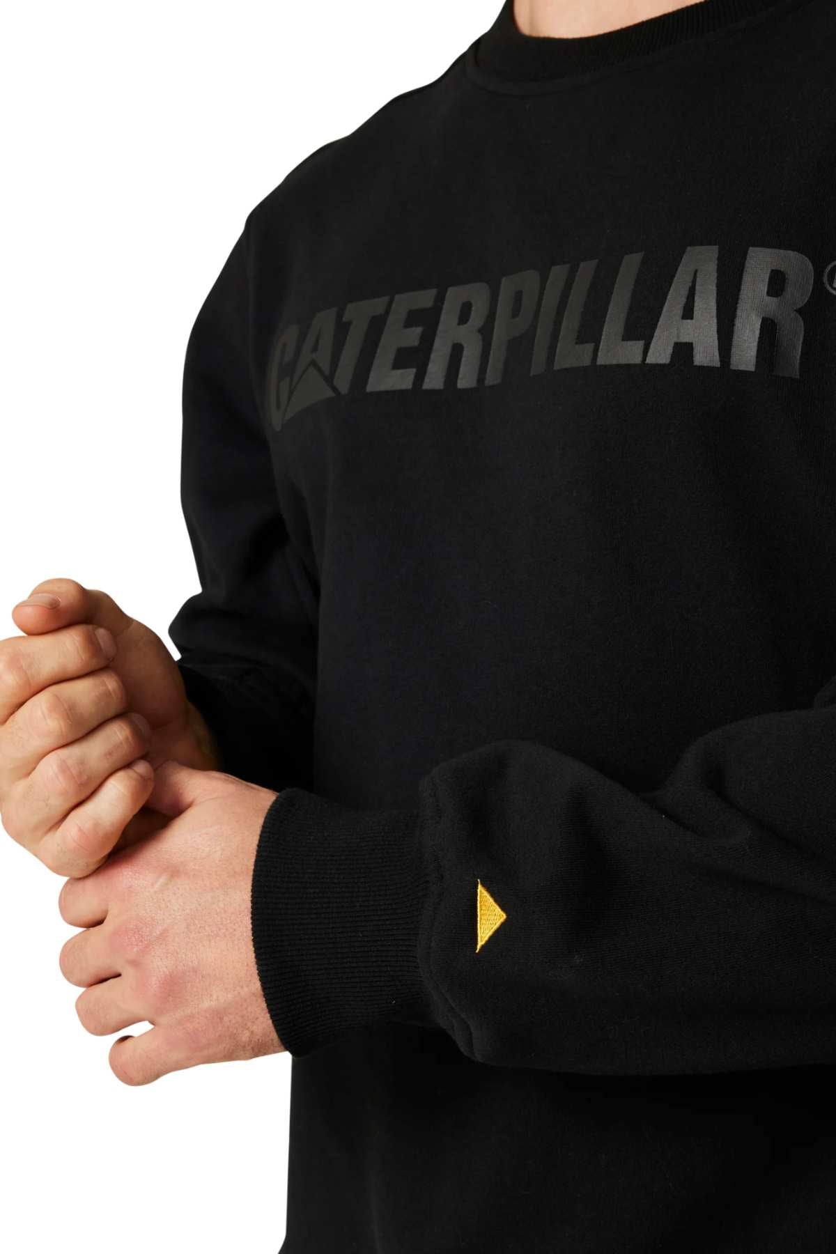 An individual clad in a black CAT Crewneck Sweatshirt, crafted from durable fabric and bearing the bold "Caterpillar" logo prominently across the chest, appears against a white background. The person is depicted from the shoulders down with their hands held in front of them.