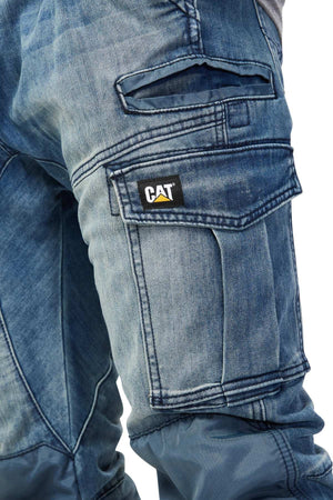 Close-up of CAT Dynamic Denim Pant in blue denim, featuring multiple pockets—including cargo and flap pockets with a visible CAT logo patch—and reinforced knee patches for extra durability.