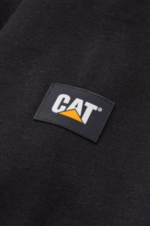 Close-up of the fabric shows a small rectangular logo patch. The patch is black with "CAT" in white capital letters and a yellow triangle beneath the "A". The dark-colored fabric, which appears to be black, suggests it could be part of the CAT Essential Hooded Sweatshirt by Caterpillar Inc.