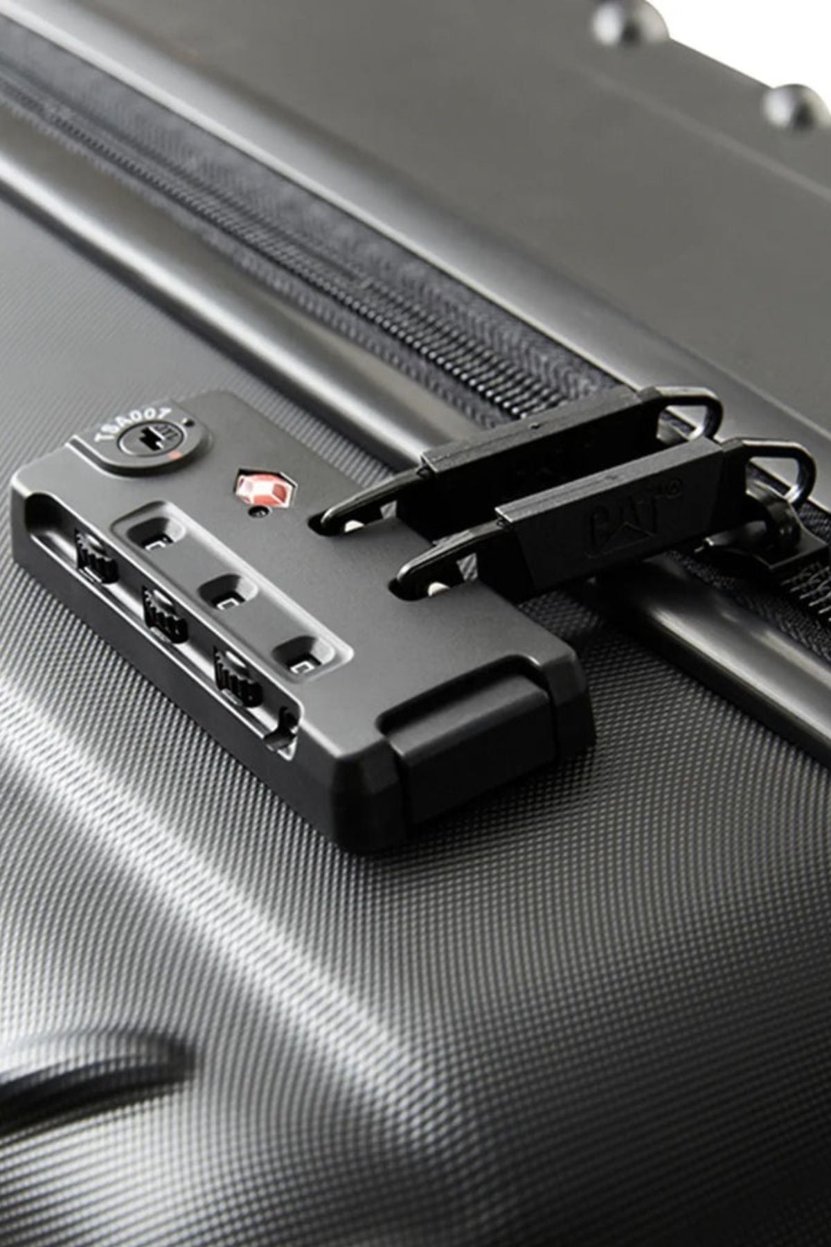 Close-up of the CAT Industrial Plate 20" Trolley, a black hard-shell carry-on with a textured, patterned finish and built-in TSA lock securing two zipper pulls.