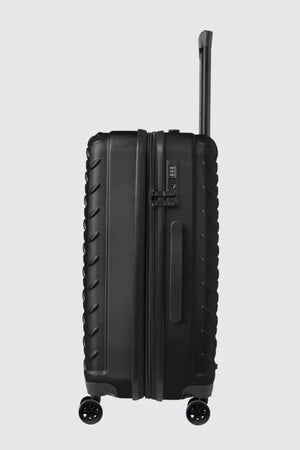 The CAT Industrial Plate 28" Trolley is a black hard-shell expandable suitcase with textured edges, four spinner wheels, a side handle, TSA lock, and an extended telescopic handle, shown upright against a light gray background.