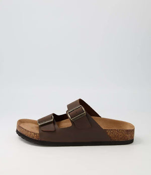 The Colorado Karra Crazyhorse Slide is a single brown leather sandal with two adjustable buckle straps, a cork footbed for comfort, and a slip-resistant black sole, displayed against a plain light background.