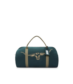 The RM Williams Nanga Canvas Bag is dark green with tan handles and straps, crafted from durable cotton canvas. It features a longhorn steer head graphic on the front and includes a small luggage tag, making it a versatile duffle bag.