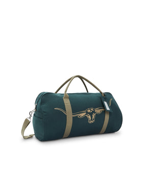 The RM Williams Nanga Canvas Bag in dark green is made from durable cotton canvas with tan handles and strap, a gold longhorn graphic, and a luggage tag on one handle, shown on a white background.