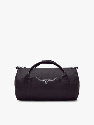 The RM Williams Canvas Ute Bag is a black duffel with water-resistant fabric, two leather handles, a top zipper, and a white embroidered longhorn skull on the front, shown against a plain white background.