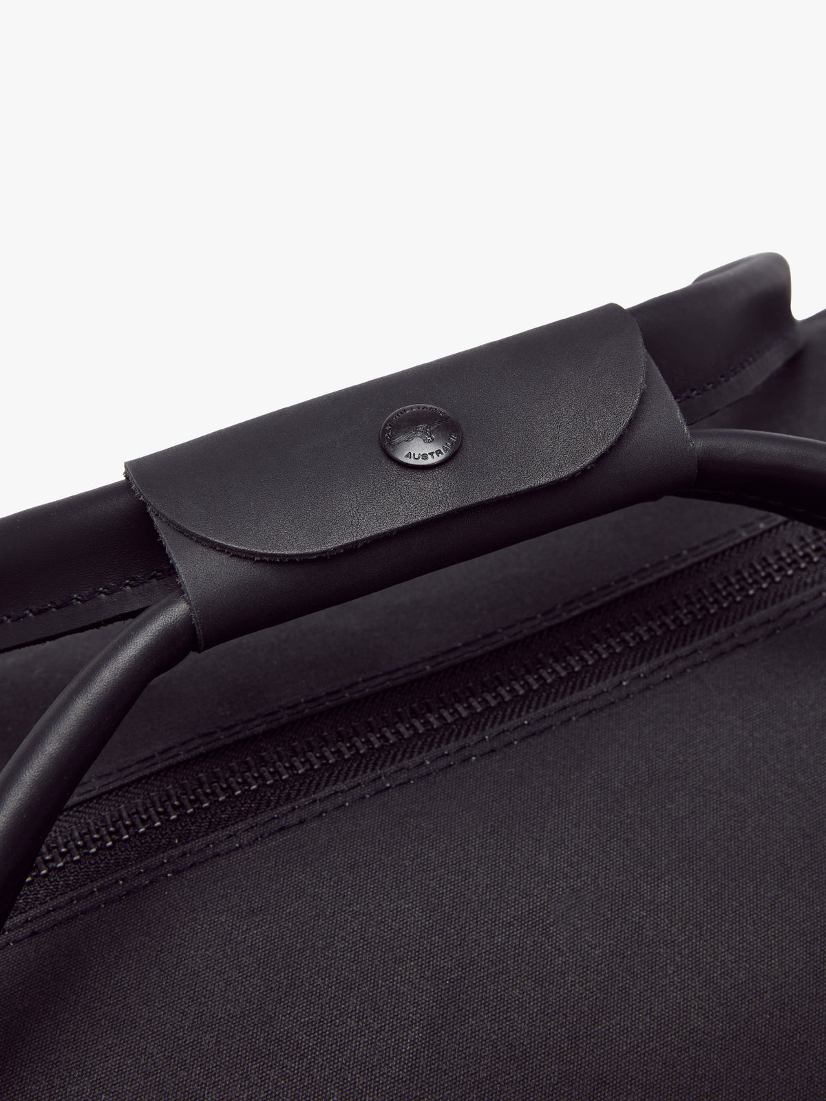 Close-up of the RM Williams Canvas Ute Bag’s water-resistant, minimalist design with sturdy leather handles featuring button detail over a fabric zipper. The durable canvas makes this sleek bag stand out in style.