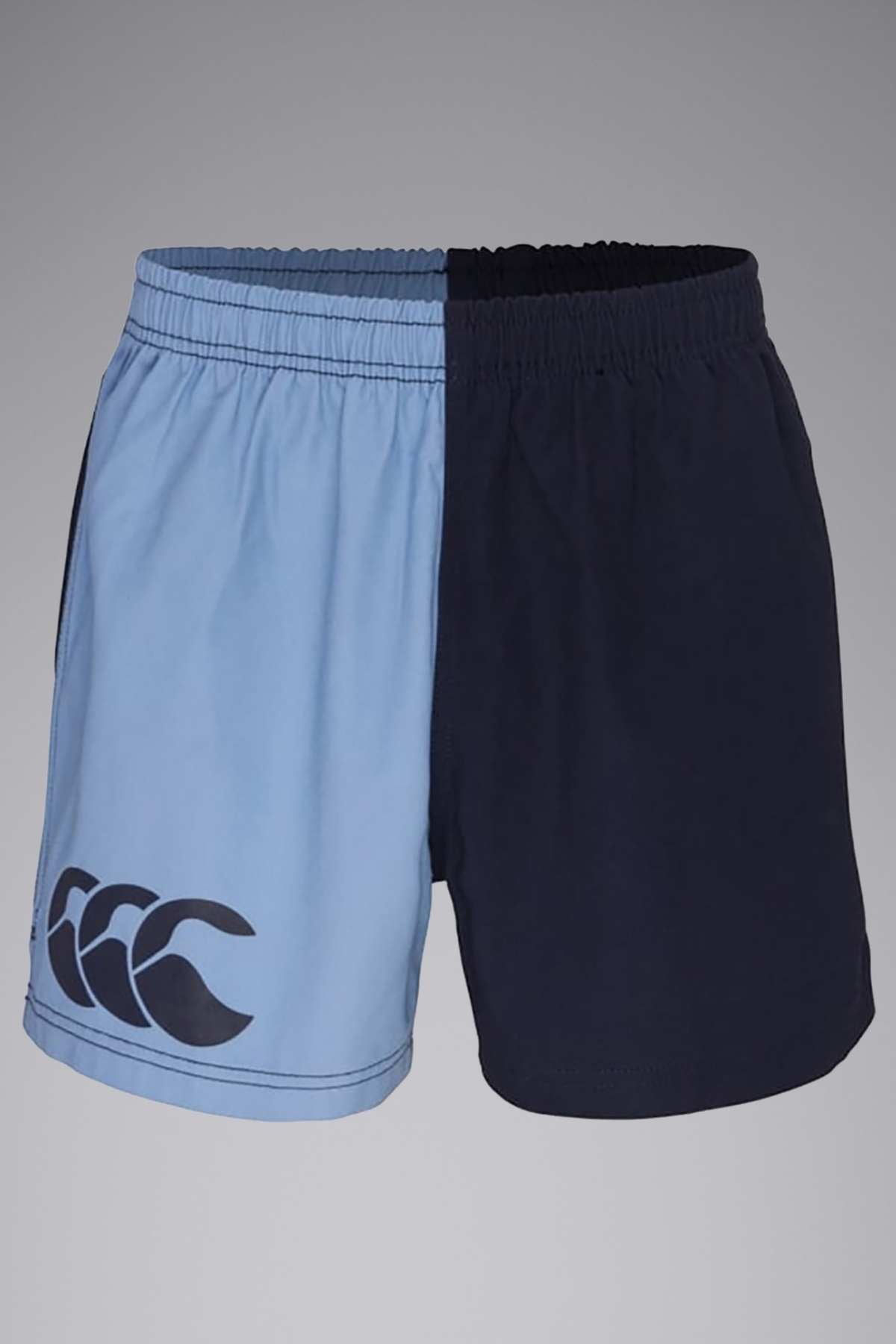 A pair of Canterbury Cotton Twill Harlequin Shorts combines light blue on the left and dark blue on the right. The light blue side showcases a large CCC print with three overlapping white and black "C" letters near the hem. Made from 100% cotton drill fabric, these shorts feature an elastic waistband.
