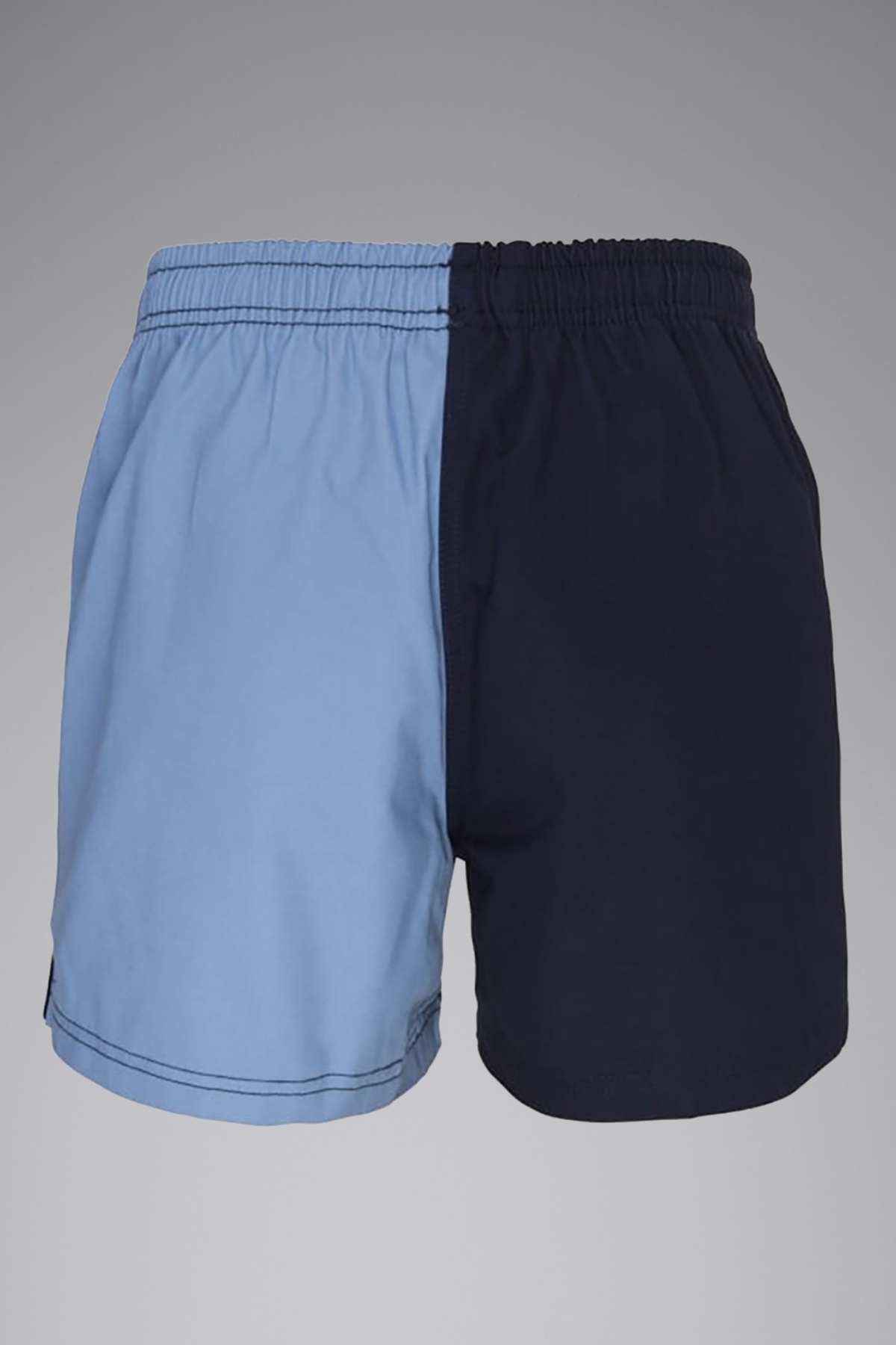 A pair of Canterbury Cotton Twill Harlequin Shorts with an elastic waistband, featuring a two-tone design; the left side is light blue while the right side is dark navy blue. Crafted from 100% cotton drill fabric, these shorts offer a simple design devoid of any visible logos or patterns, set against a plain gray background.