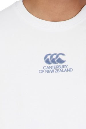 Close-up of a person wearing the Canterbury Heritage T-Shirt, featuring the CCC logo and "Canterbury of New Zealand" embroidered in blue on the chest. Only the lower neck and upper chest are visible.