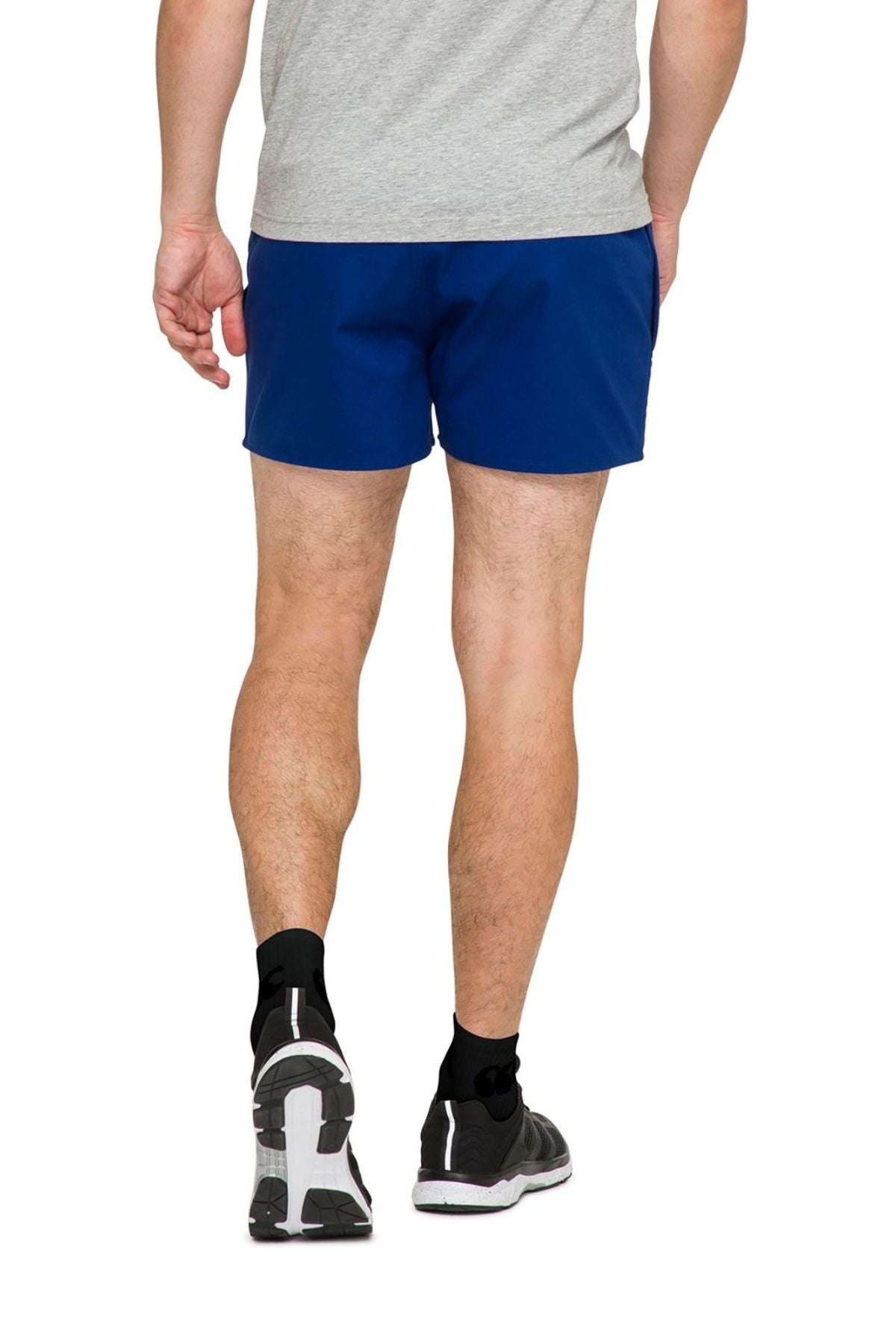 A person wearing a gray T-shirt, Canterbury Rugged Drill Short with an elasticated waist and tape side pockets, black socks, and black running shoes is walking away from the camera on a plain white background.