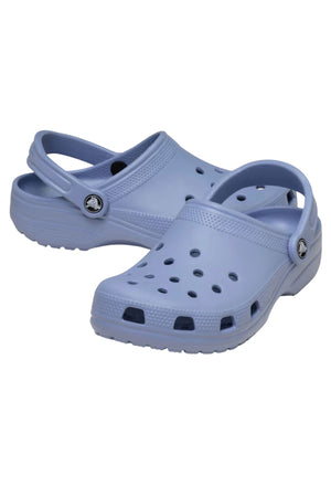 A pair of Crocs Classic Clog in light purple, featuring ventilation holes, adjustable heel straps, and textured soles. The lightweight clogs are displayed at an angle, highlighting the top and side views.