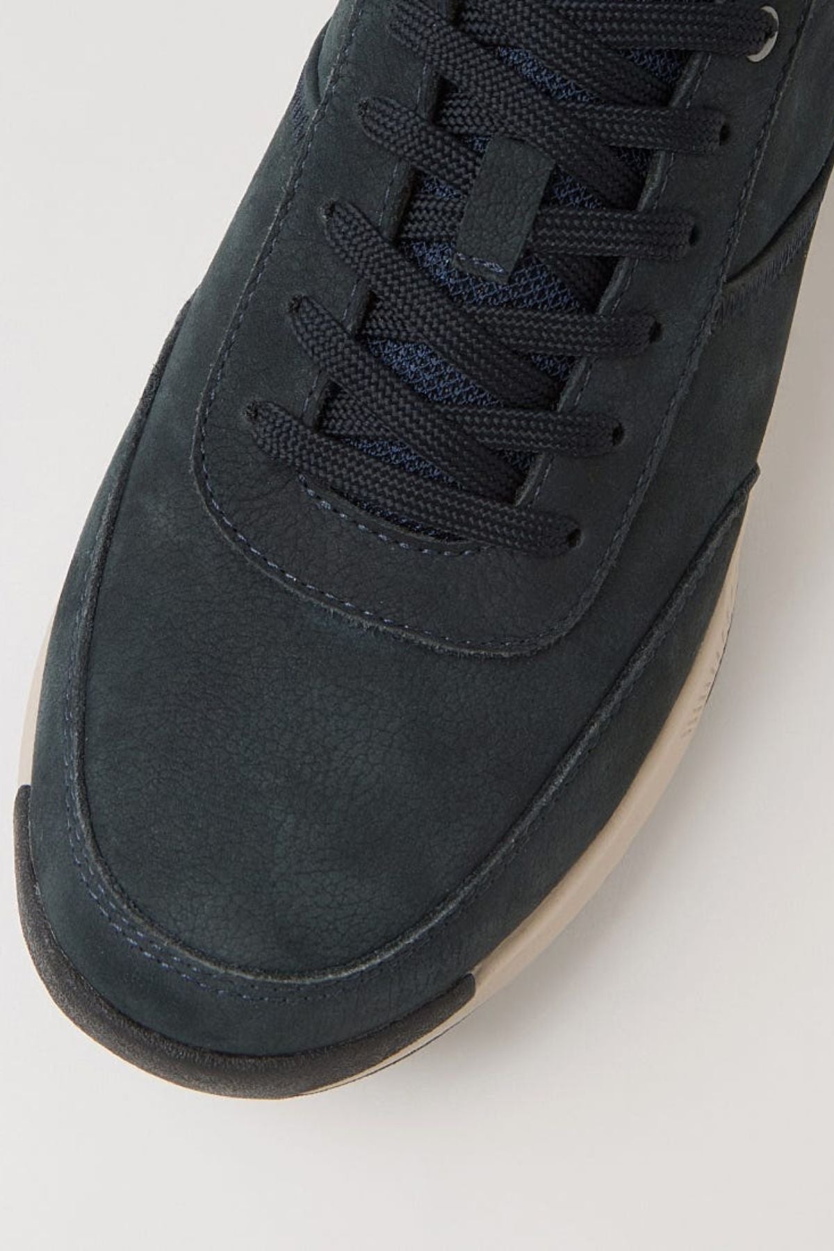 Close-up of the toe and laces of the Colorado Suzuki Shoe, a dark navy blue sneaker with black laces, a white slip-resistant sole, and premium leather, shown against a plain light background.