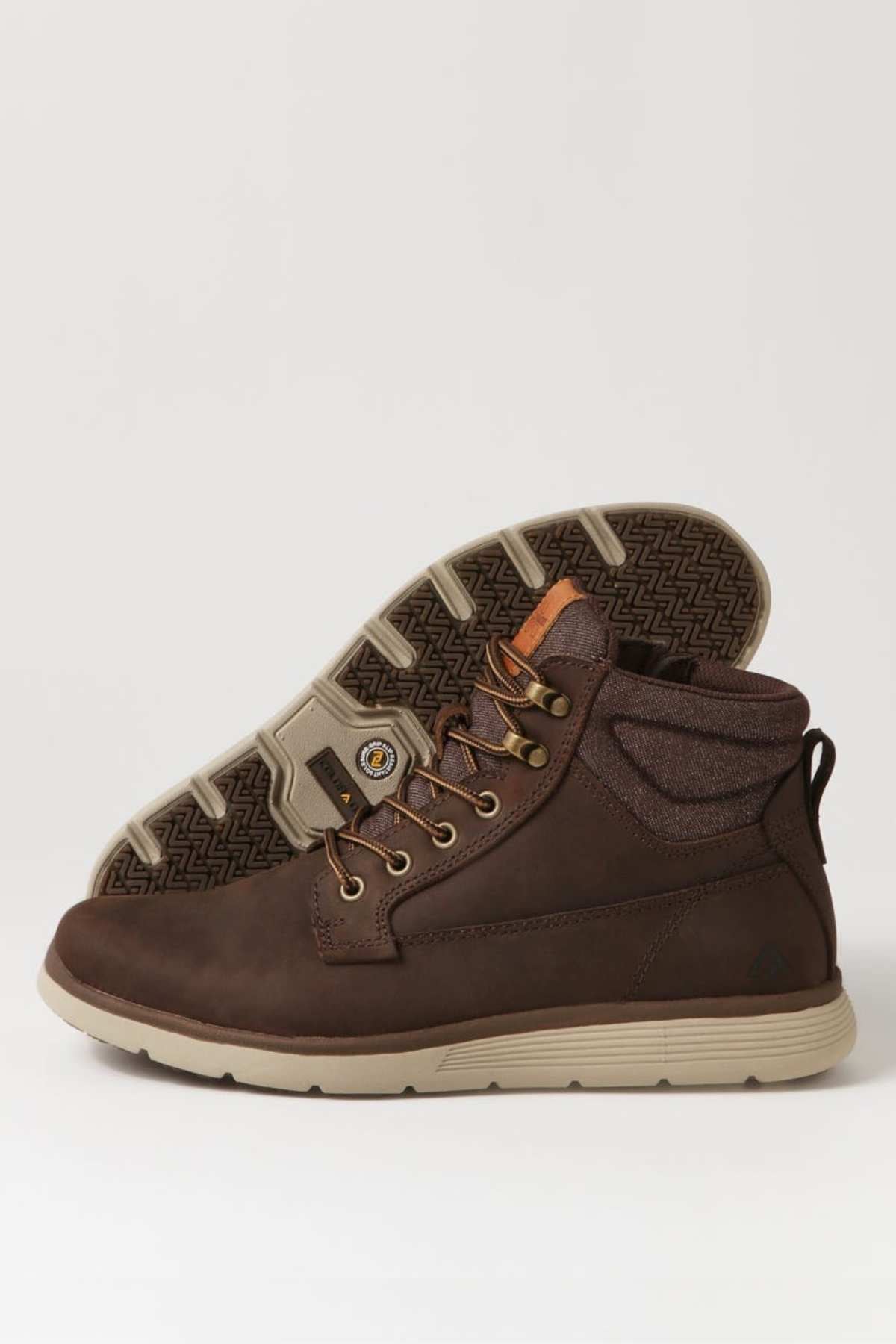 A pair of brown leather Colorado Yrbud Boots with beige, slip-resistant soles. One boot stands upright and the other is on its side, showing the patterned tread. Features include metal eyelets and padded collars for comfort.