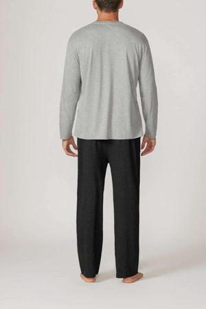 A man stands barefoot with his back to the camera, wearing the Contare Country Bamboo Cotton Long Sleeve Set in gray and loose-fitting dark gray pants, set against a plain light background.