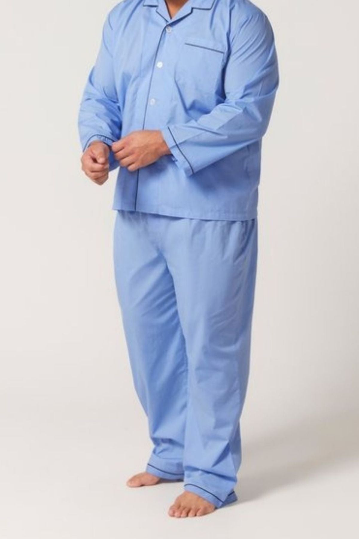 A person stands barefoot on a light background, wearing the Contare Country Cotton Rich Long Sleeve Classic Set with matching light blue pants. The comfortable, loose-fit sleepwear is pictured without their head visible.