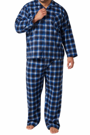 A man stands barefoot against a white background wearing the Contare Country Winter Flannelette PJ Set, a matching blue, black, and white plaid pajama set made from 100% cotton.