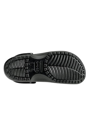 The image shows the underside of a Crocs Classic Clog in black, featuring a textured, grooved sole with various tread patterns for grip. The sole has the brand name "Crocs" embossed in the middle. This lightweight design appears to be aimed at providing traction and durability, perfect for any water adventure.
