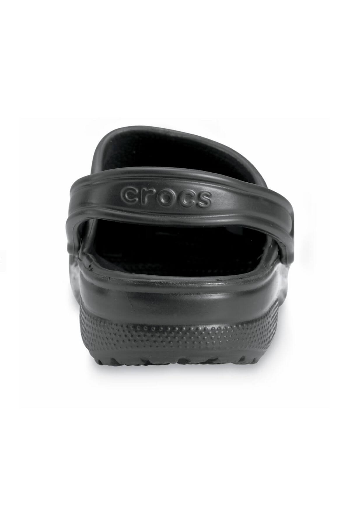 A close-up view of a single Crocs Classic Clog in black from the back, highlighting its textured sole and adjustable heel strap with "Crocs" embossed on it. Ideal for any water adventure, this lightweight footwear combines comfort and durability.