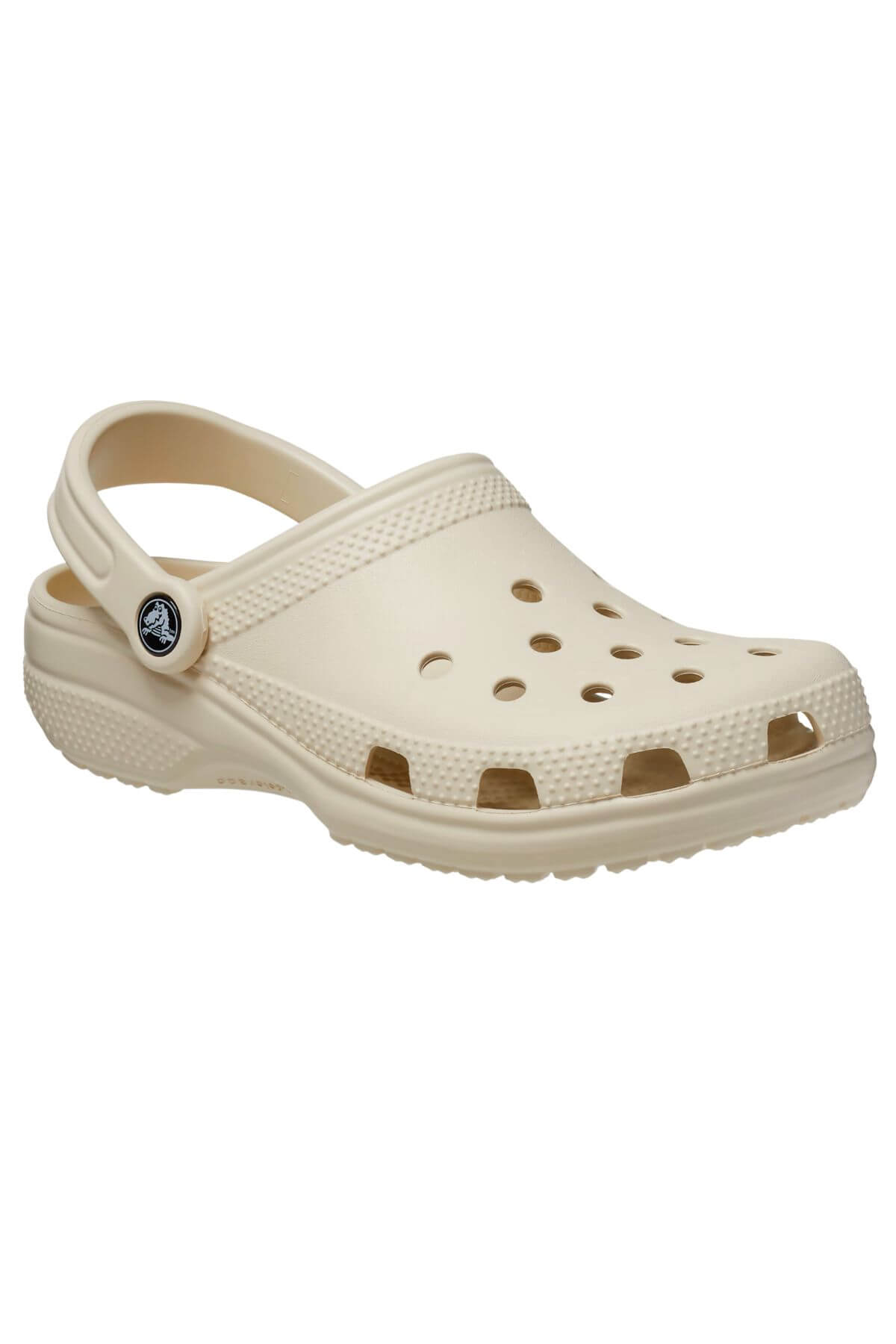 The Crocs Classic Clog is a lightweight, beige slip-on shoe with ventilation holes, ensuring breathable comfort. It features a secure fit with a small circular logo near the strap for style.