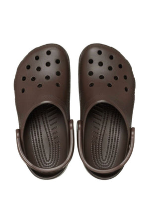 A pair of Crocs Classic Clog in dark brown with ventilation holes and adjustable heel straps, shown from above on a white backgroundβlightweight, breathable footwear ideal for water adventures.