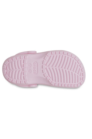 The image shows the bottom view of a Crocs Classic Kids Clog in light pink, featuring a textured sole with the Crocs logo and size near the heel—ideal for comfortable kids' footwear.