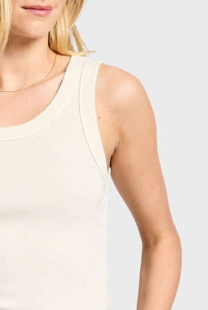 A person is wearing the Academy Women Essential Rib Tank, made from light-colored cotton elastane for style and comfort. The image focuses on the chic design, highlighting the upper body and shoulders against a plain background.