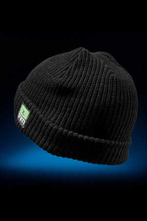 The FXD CP-10 Knit Ribbed Beanie is black, made from 100% acrylic, and features a green and white rectangular front patch. It’s shown against a dark background with a subtle blue gradient below.