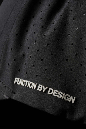 A close-up of the FXD CP-12 Tech Baseball Cap's black fabric reveals small perforated holes and the embossed text "Function by Design" in white. Its lightweight construction and quick-drying performance polyester emphasize its superior design.