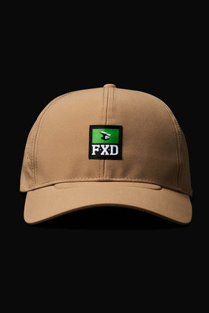 The FXD CP-12 Tech Baseball Cap in tan features a curved brim, quick-dry performance polyester, a green and black FXD patch with a white design, and an adjustable snap-back. Displayed on a black background.