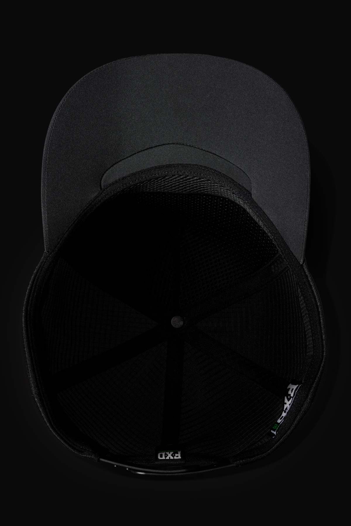 The FXD CP-13 Trucker Cap in black is pictured from below, revealing its breathable mesh interior and an adjustable snap-back strap, with the brim visible at the top against a dark background.