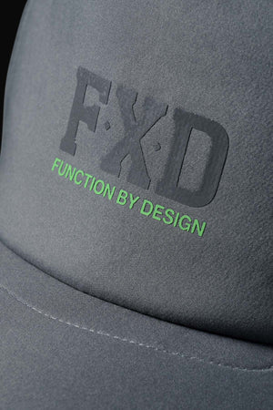 Close-up of the FXD CP-13 Trucker Cap in gray, made from breathable fabric, with raised black "FXD" lettering and green "FUNCTION BY DESIGN" text below.