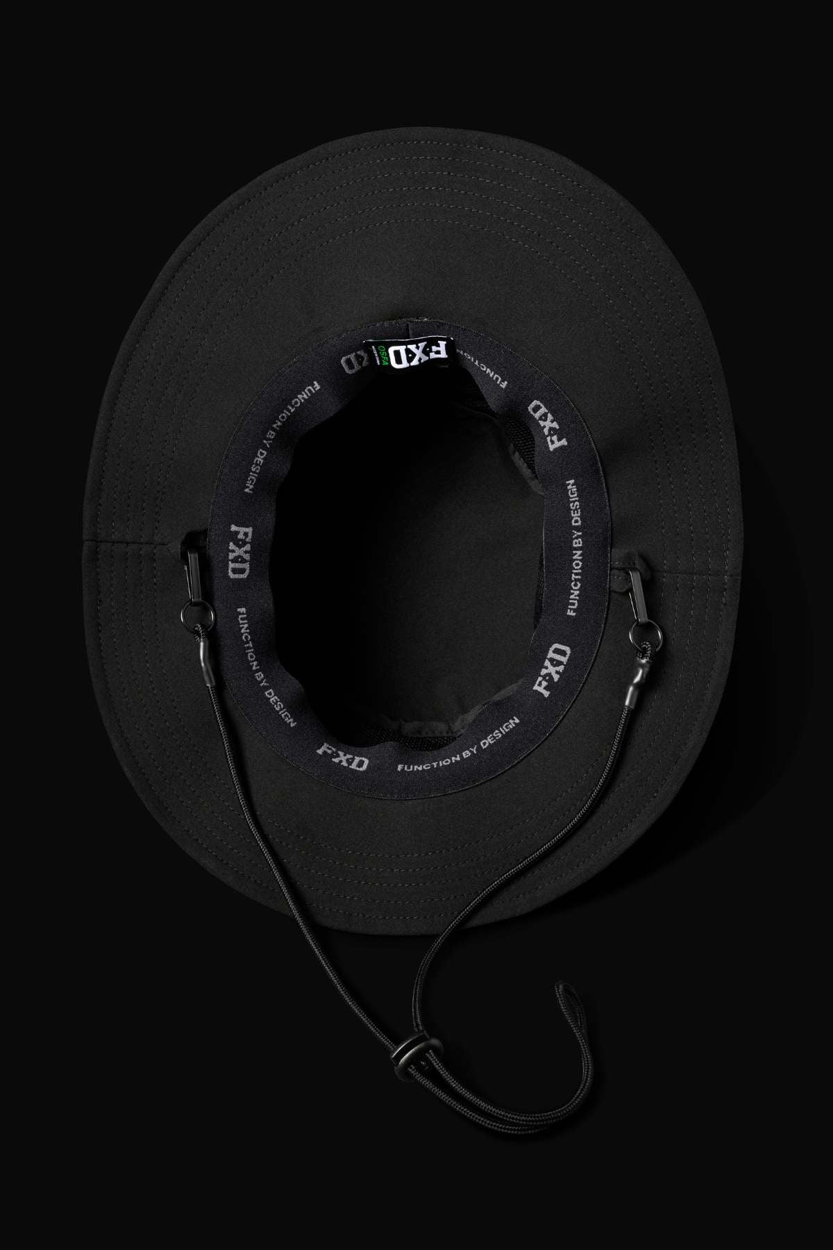 The FXD CP-14 Boonie Hat, shown from above against a dark background, is black with lightweight construction, ventilation eyelets, an inner band labeled "FXD," and an adjustable chin strap for sun protection.
