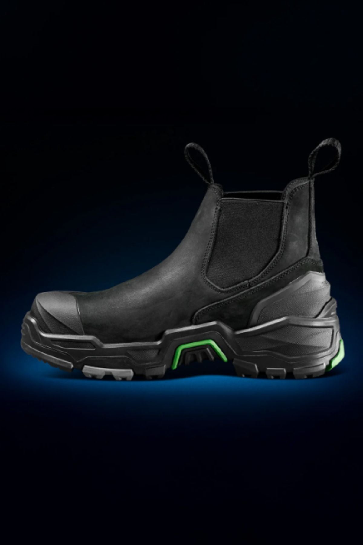 The FXD DURA X-3 Slip On Work Boots feature a black, rugged design with green accents, front and back pull tabs, a thick NITROCORE sole system, reinforced toe, and puncture-resistant build—perfect for tough jobs in dark environments.