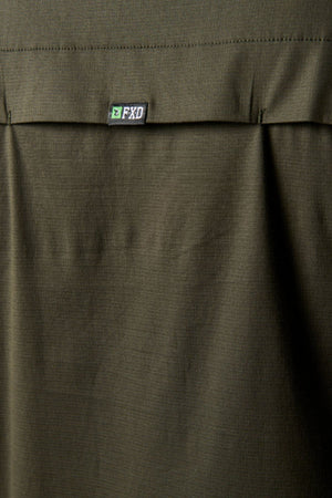 Close-up of olive green stretch fabric with a flap and small black and white FXD logo tag, part of a pocket on the FXD LSH-3 Vented Work Shirt.