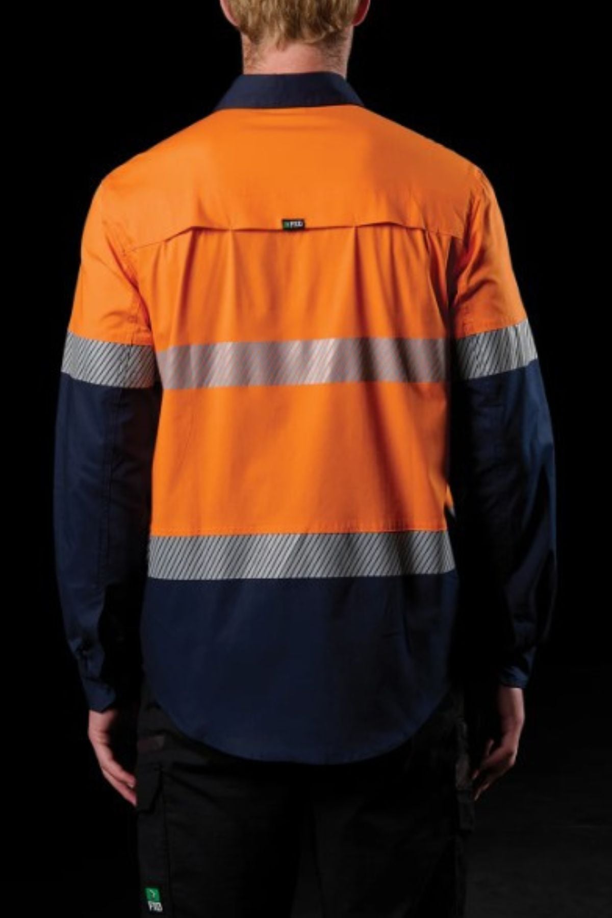A person is seen from behind wearing the FXD LSH-4T Work Shirt, featuring a hi-visibility orange upper, navy lower half and sleeves, and two reflective stripes across the back and arms, set against a black background.