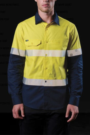 A person wearing the FXD LSH-4T Work Shirt in yellow and navy, featuring segmented reflective tape, long sleeves, a front pocket, and lightweight durable stretch fabric, stands against a dark background.